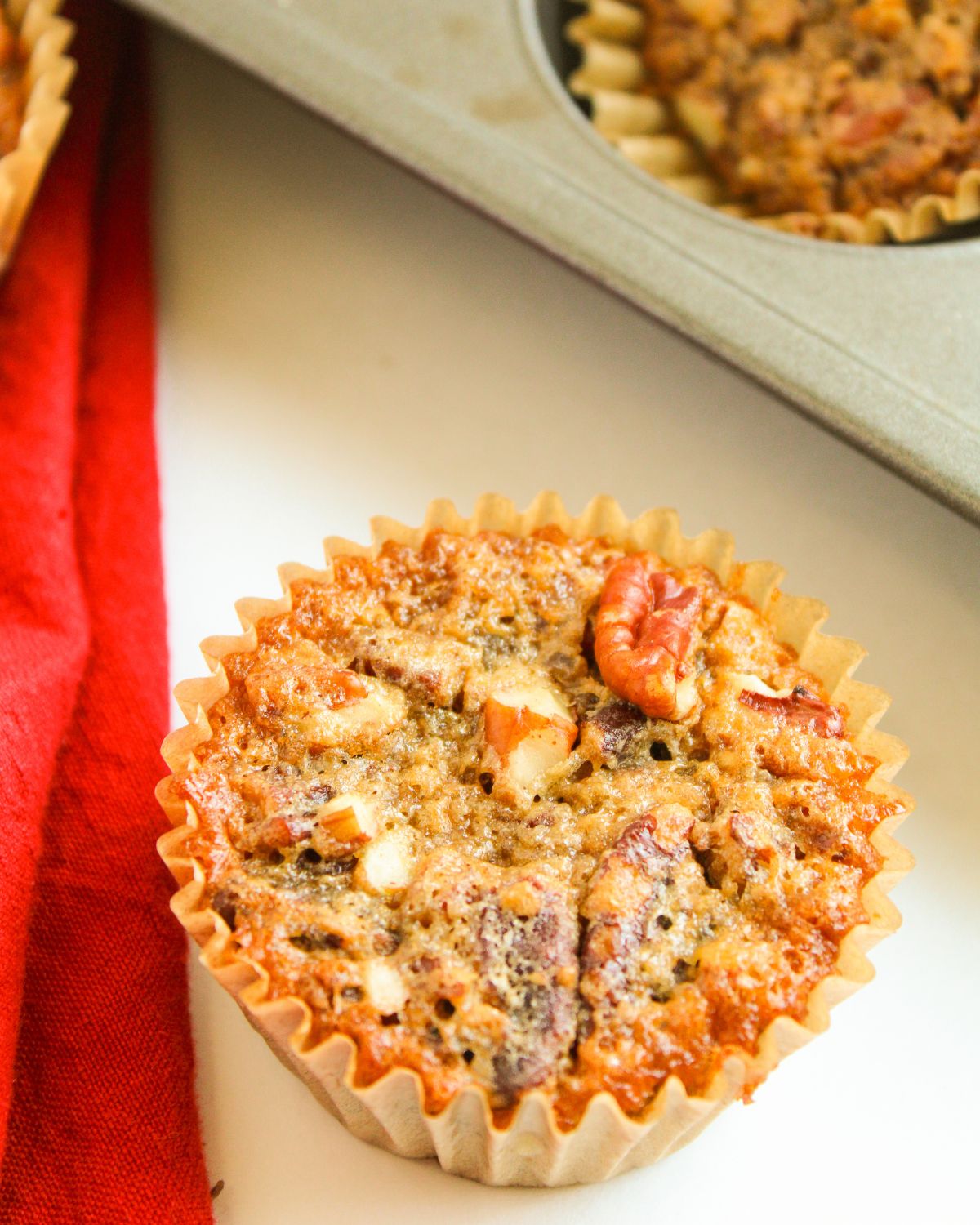 Pecan Pie Muffin on a plate topped with chopped pecans. 