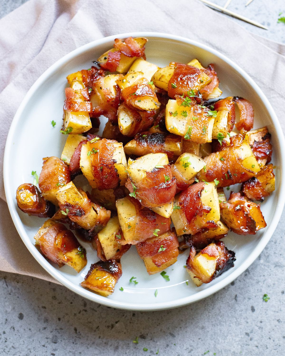 A white plate with bacon wrapped potatoes.