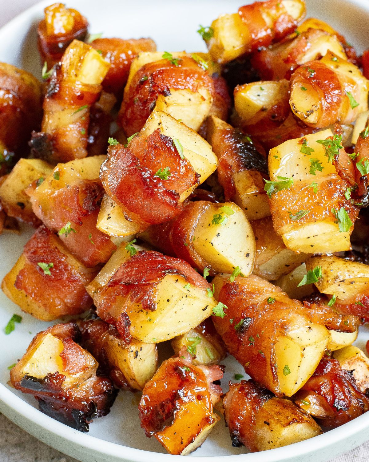 Bacon wrapped potato appetizers ina. bowl topped with chopped fresh parsley.