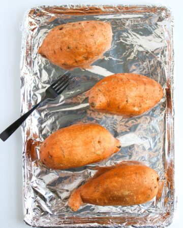 Sweet potatoes on a baking sheet ready to be baked.