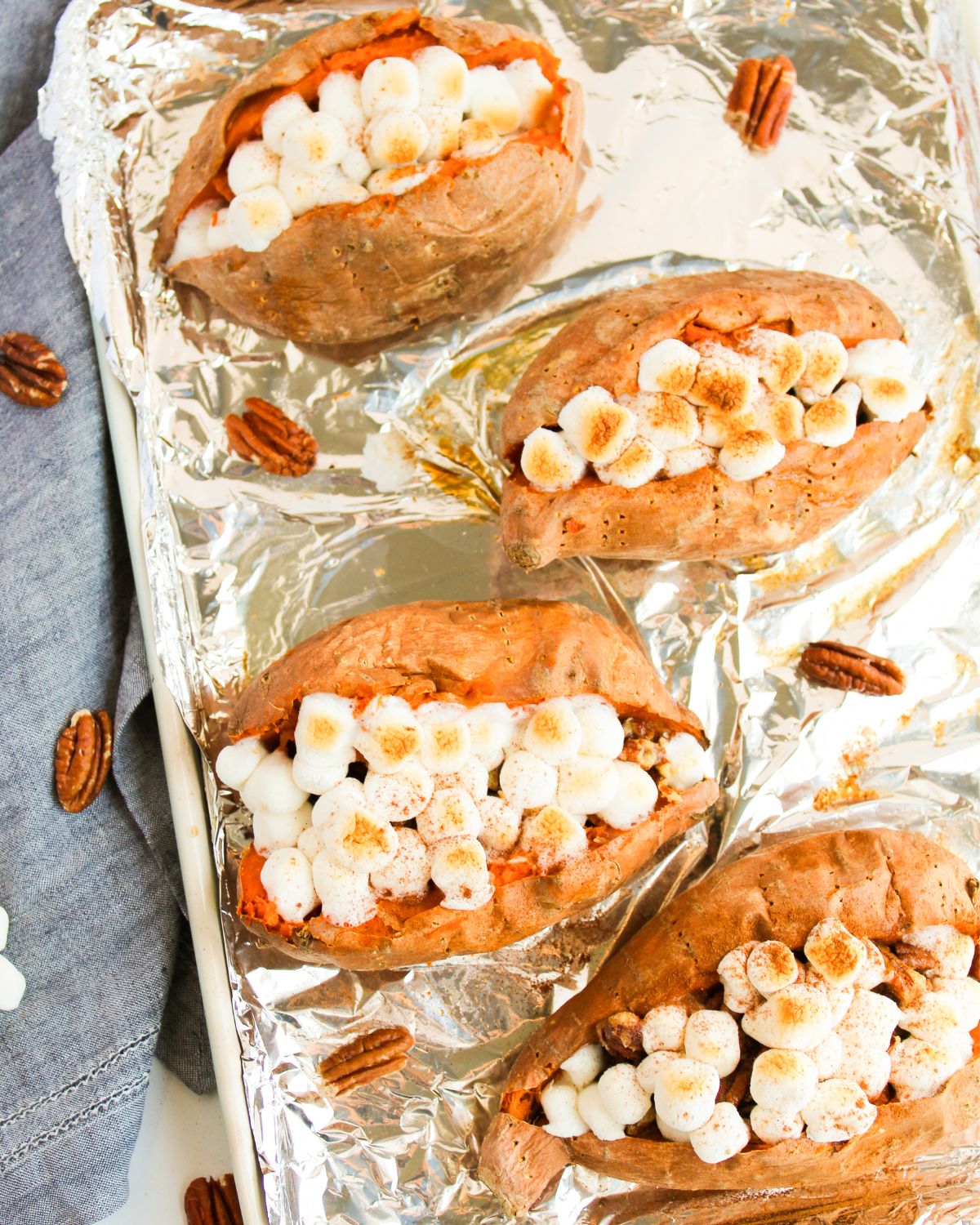 A baking tray with sweet potatoes stuffed with marshmallows and a pecan butter.