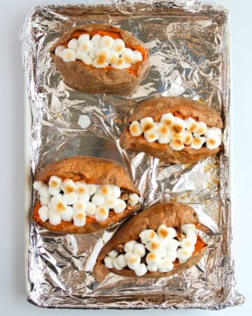 Baked stuffed sweet potatoes with a pecan butter filling topped with marshmallows.