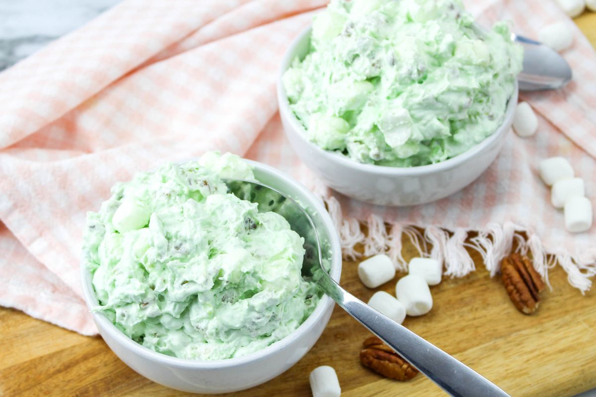 Two white bowls with pistachio pudding, pecans, pineapple to make a classic Watergate Salad.