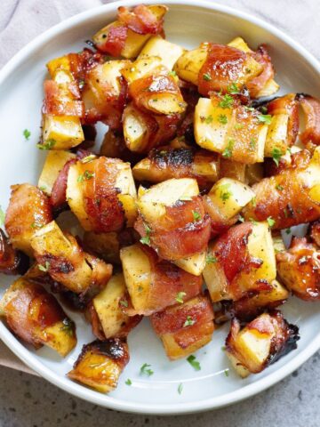 Bacon wrapped potato slices with a honey glaze on a plate.