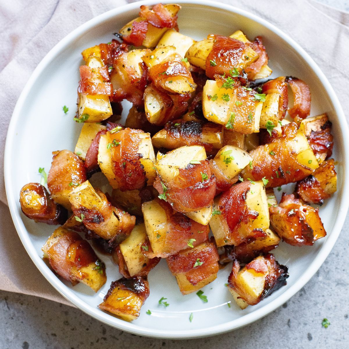 Bacon wrapped potato slices with a honey glaze on a plate.
