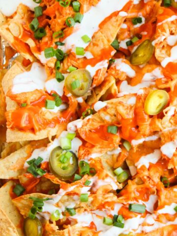 Baked buffalo chicken nachos topped with chedar cheese and ranch dressing.