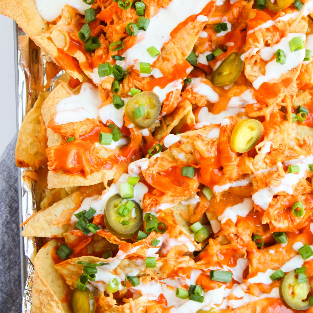 Baked buffalo chicken nachos topped with chedar cheese and ranch dressing.