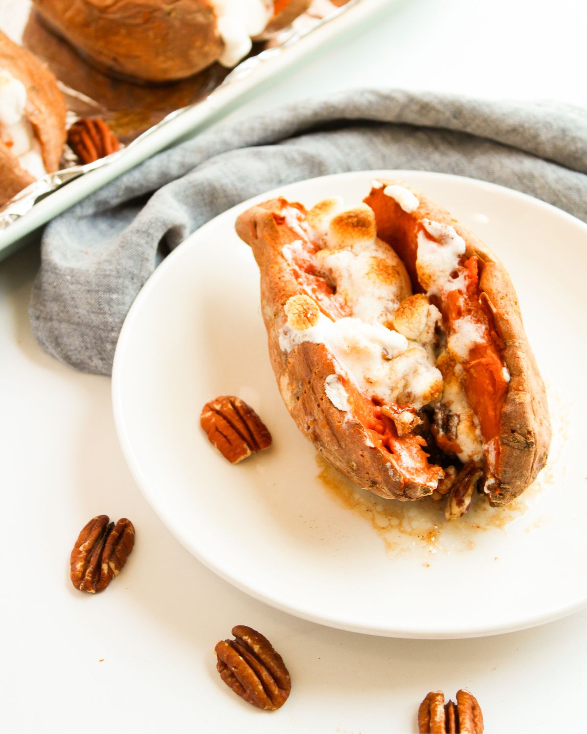 A baked sweet potato with brown sugar, pecans, and mini marshmallows.
