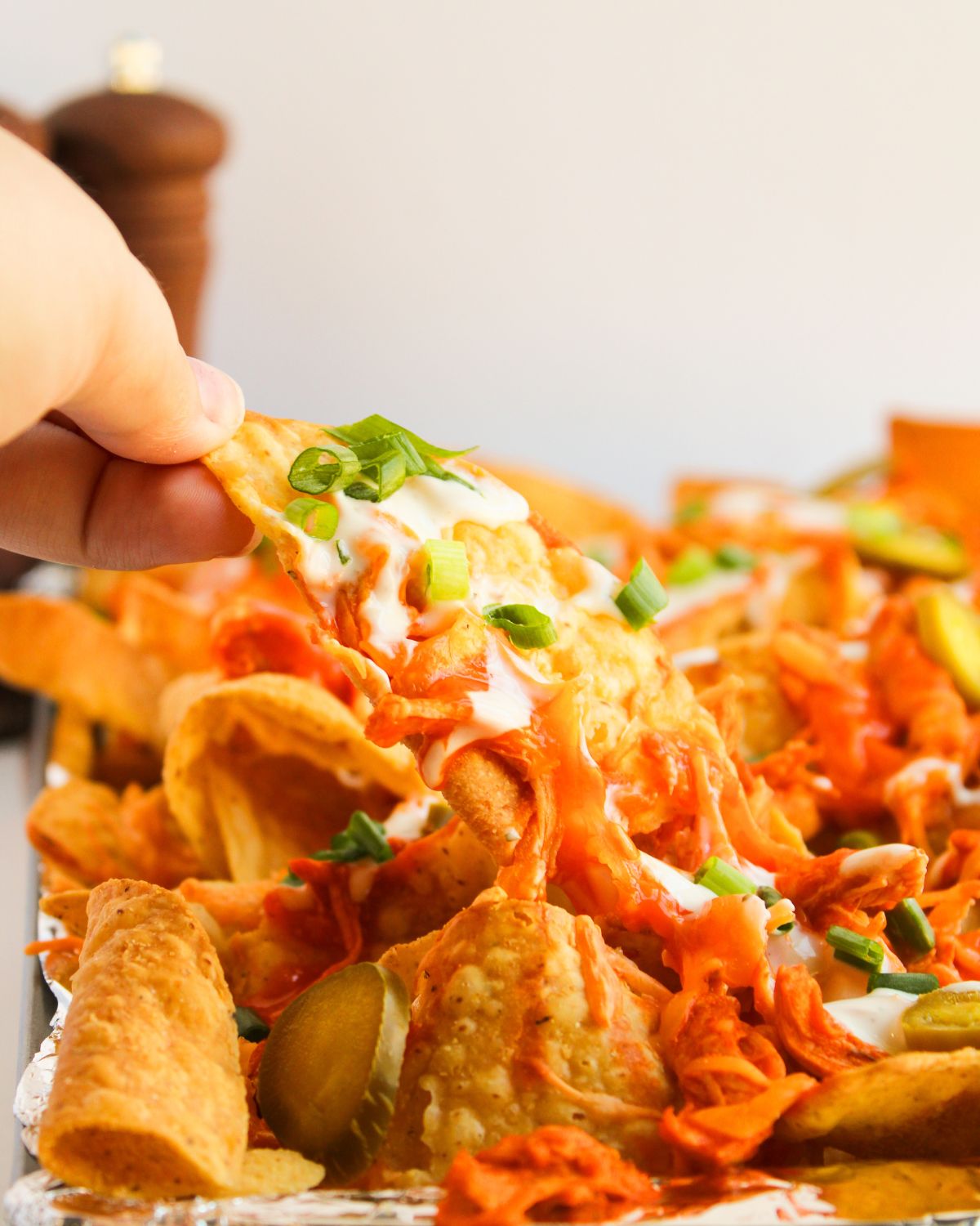 Baked buffalo chicken being picked up with a cheesy topping. 