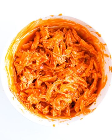 Shredded chicken with buffalo sauce to make nachos.
