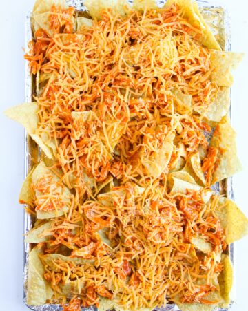Buffalo chicken nachos with shredded chicken topped with cheese.