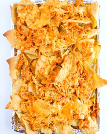 Baked buffalo chicken tacos with cheese on corn tortillas.