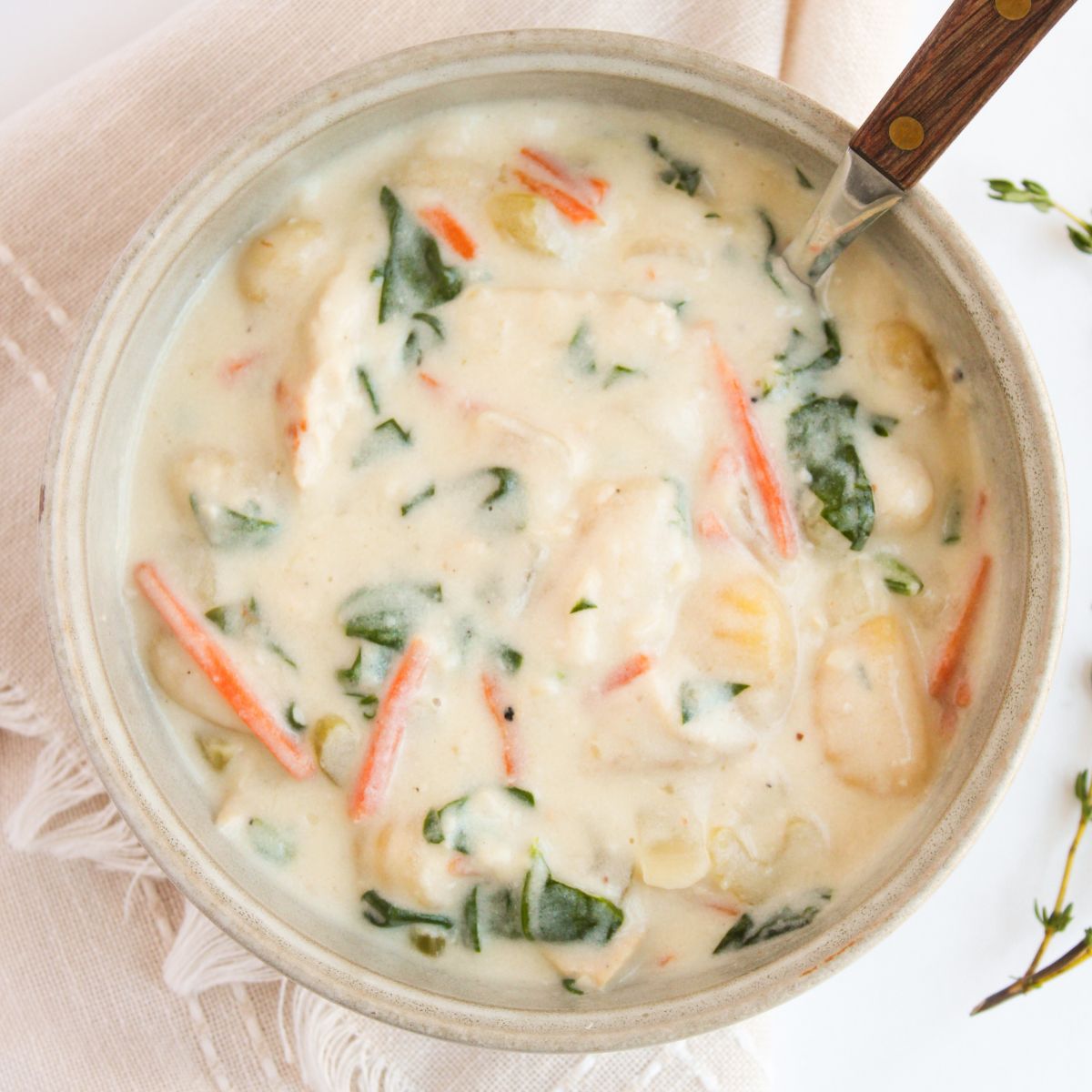 Creamy chicken gnocchi soup with spinach and shredded carrots in a bowl.