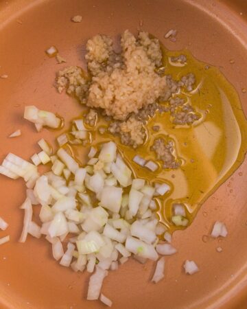 A large pan with onions sauteeing for collard greens with ham hocks.
