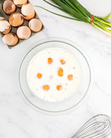 A glass bowl with eggs to make a ham and egg casserole.