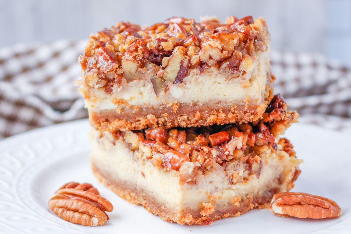 Stacked pecan pie cheesecake bars on a plate.