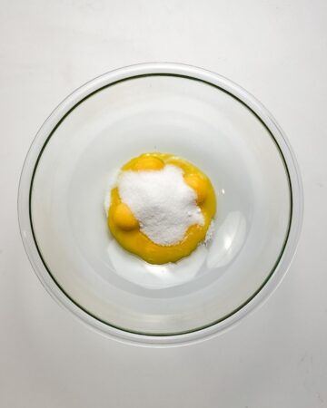 Egg yolks and white sugar in a bowl to make pumpkin creme brulee. 