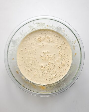 A glass bowl with whipped egg yolks and white sugar to make creme brulee. 