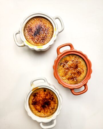 Three ramekins with creme brulee topped with sugar ready to be served.