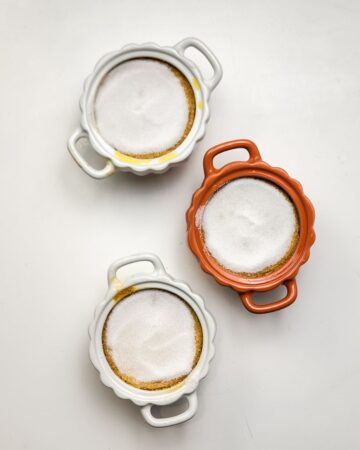Three ramekins with pumpkin custard made into creme Brulee topped with white sugar.