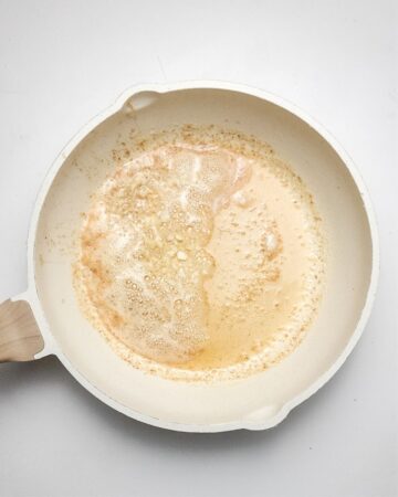 A pan with butter melting in a skillet to make chicken pot pie topped wuith biscuits.