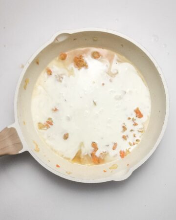 A skillet with flour and chicken stop and veggies to make the base for a chicken pot pie. 