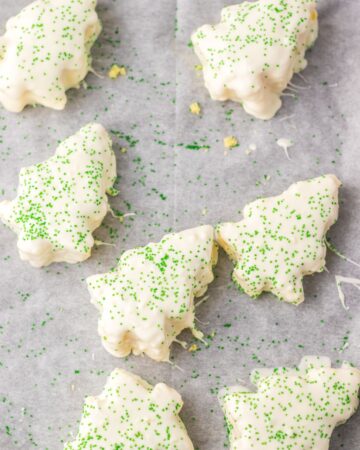 Christmas tree cutout cakes with white icing and green sprinkles. 