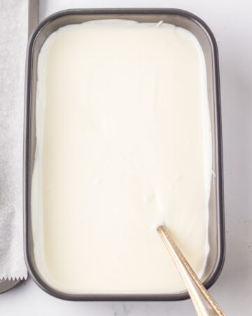 A bowl of mleted white chocolate for christmas tree cakes.