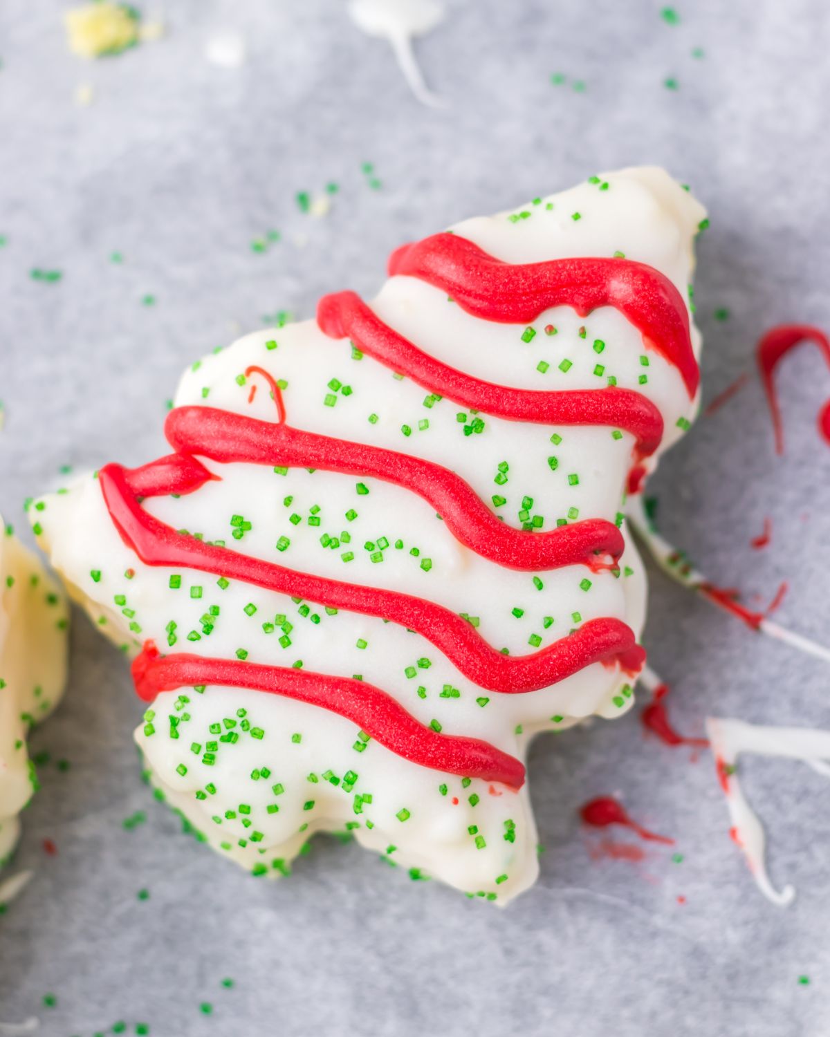 Little Debbie Christmas tree cake copycats on a baking tray with red icing stripes and green sparkles. 
