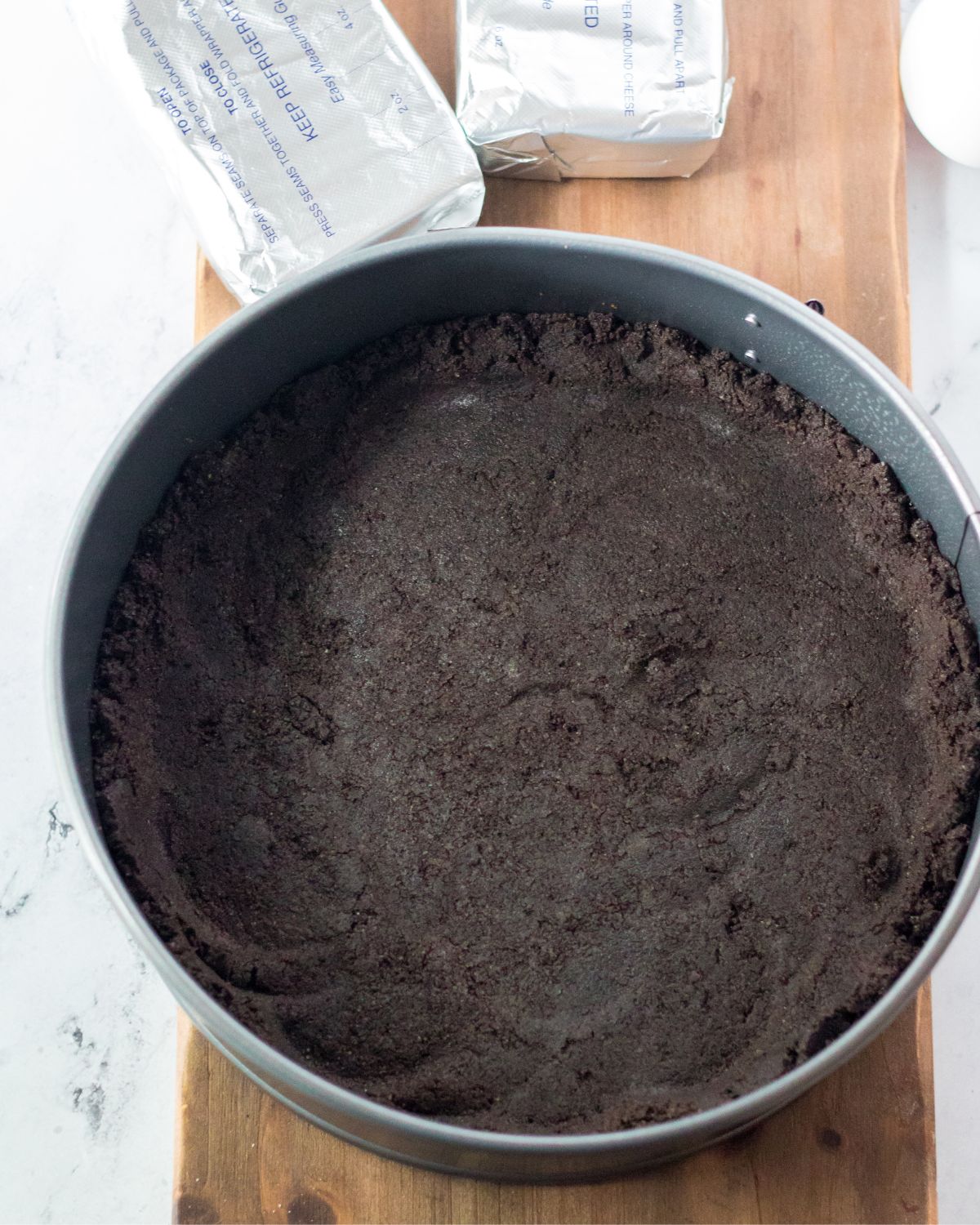 A springform pan with a chocolate oreo cheesecake crust.