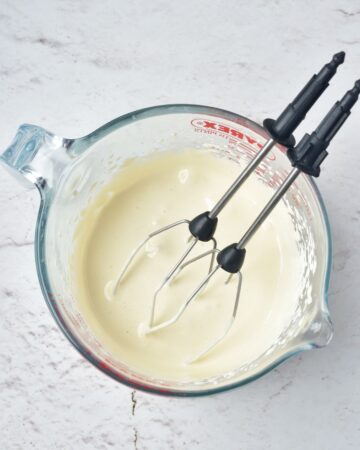A glass measuring cup with heavy cream whipped for egg nog. 