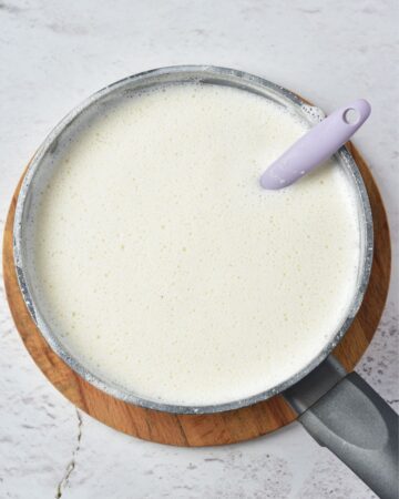 A sauce pan with eggnog mixing whipped cream and yolks. 