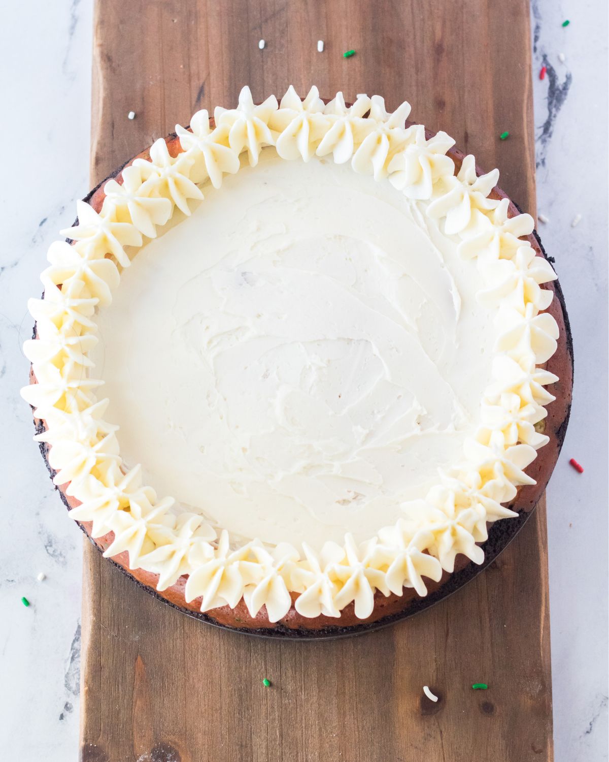 A festive cheesecake with peppermint flavor and a buttercream frosting going on the cheesecake.