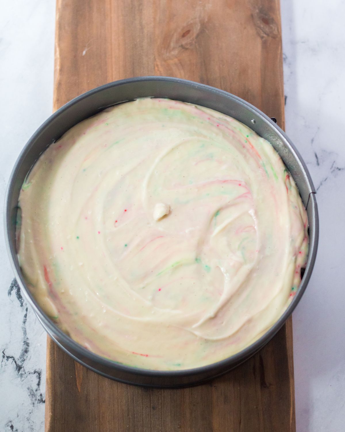 A springform pan with a Christmas cheesecake ingredients in the pan.