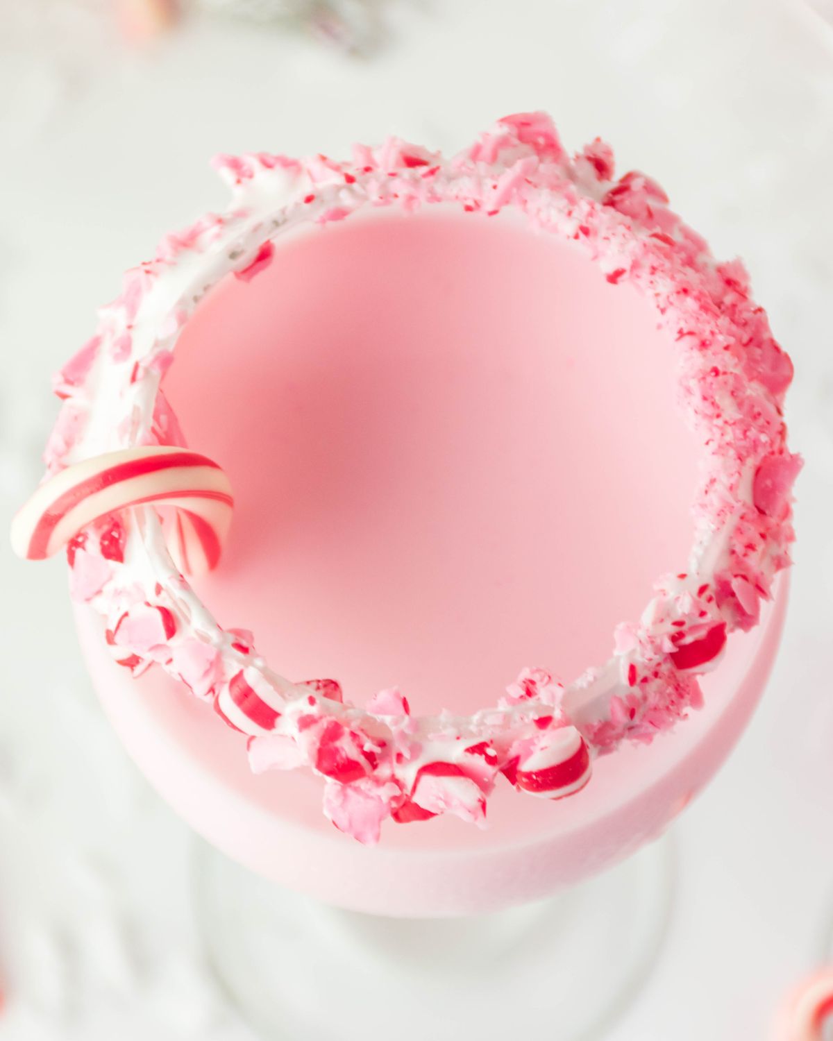 A peppermint cocktail in a glass with a candy cane.