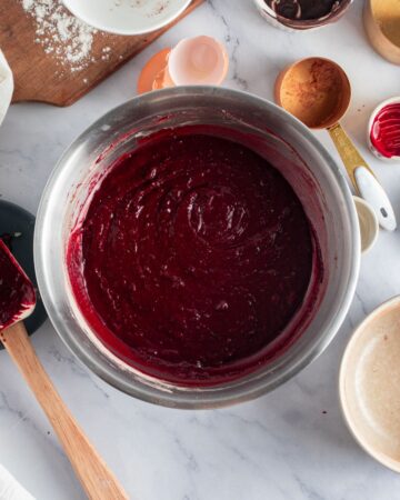 A mixing bowl with red velvet brownie ingrdients.