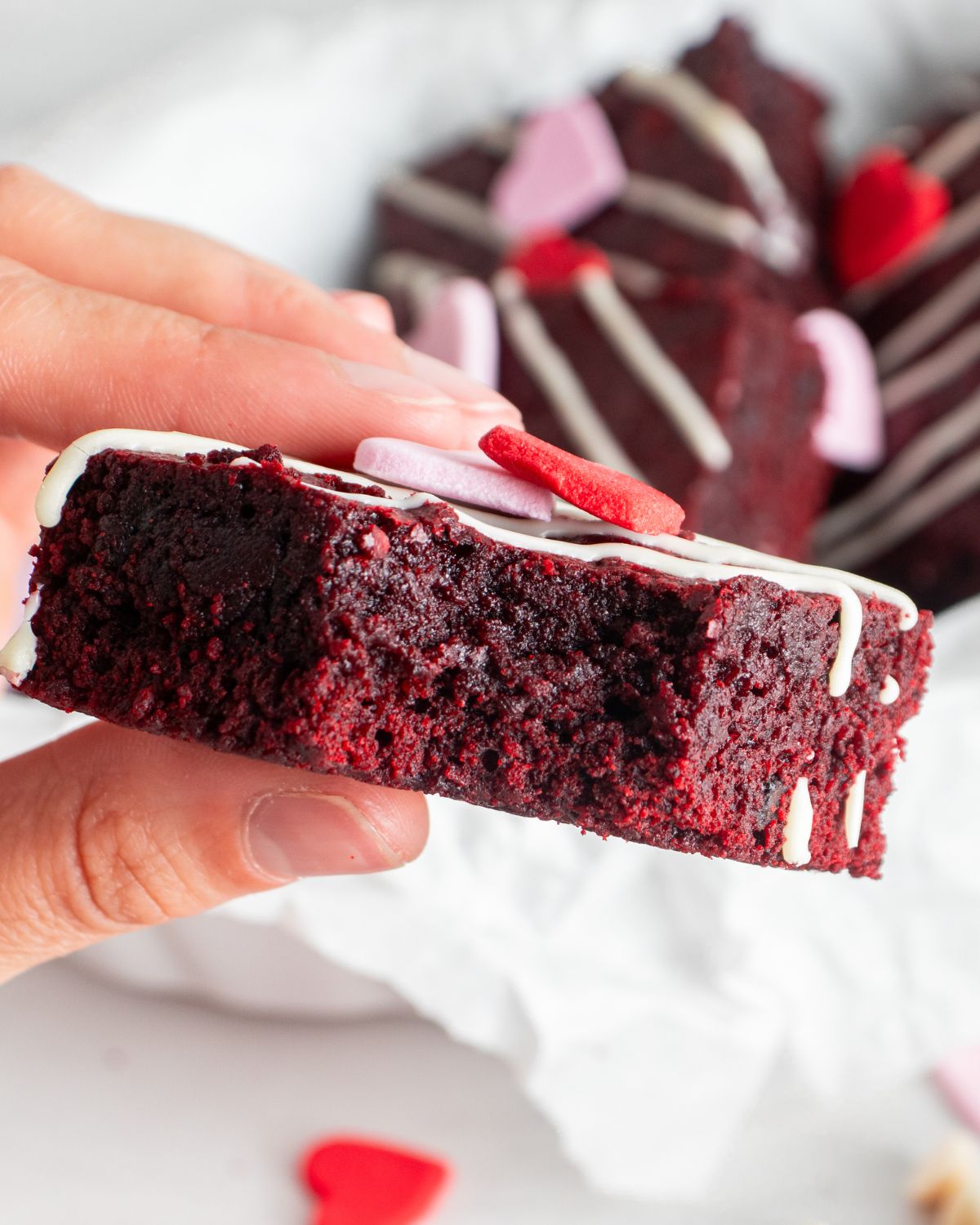 A red velvet brownie topped with a white icing. 
