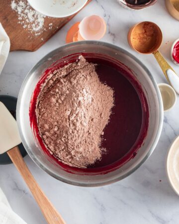 A mixing bowl with cocoa powder and red get infused brownie batter. 