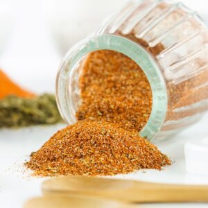 DIY blackening seasoning in a glass jar spilled out on a platter.