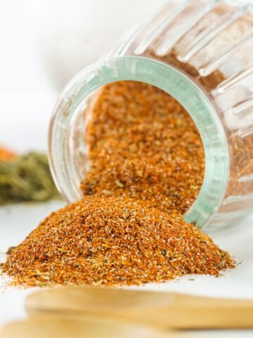 DIY blackening seasoning in a glass jar spilled out on a platter.