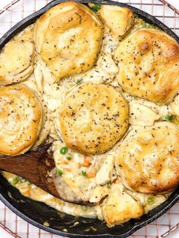 Chicken pot pie with biscuits in a cast iron pan.