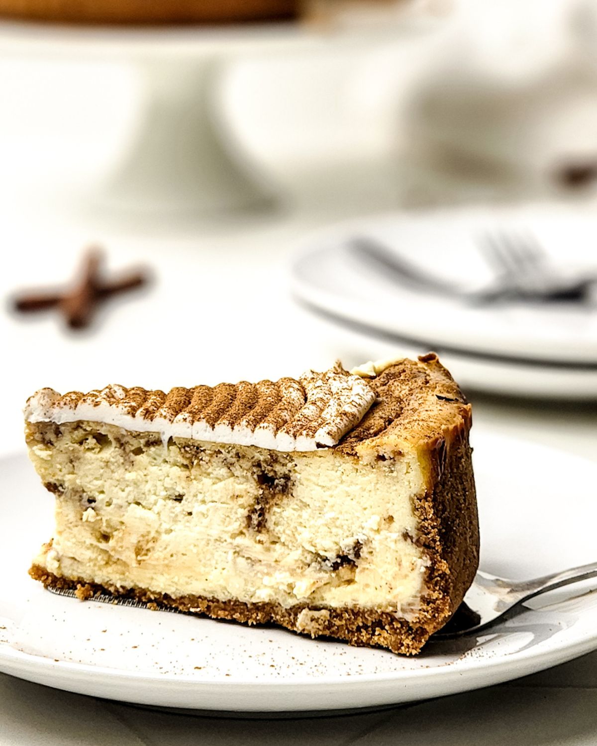 A slice of cinnamon roll cheesecake on a plate. 