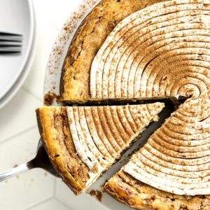 Cinnamon roll cheesecake with a slice being cut.
