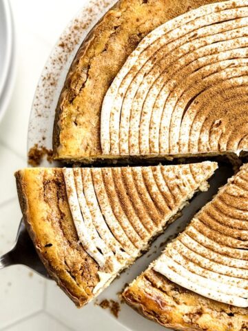 Cinnamon roll cheesecake with a slice being cut.