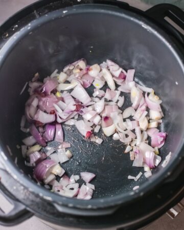 Instant Pot with red lentils being sauteed for lentil stew.