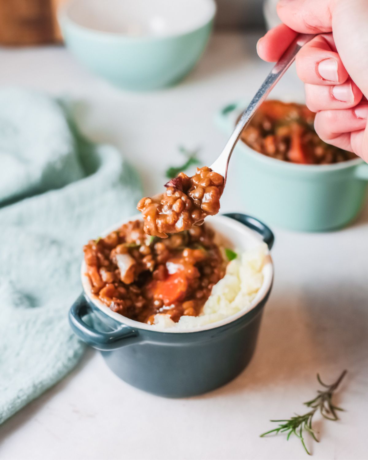 Lentil stew in a bowl with mashed potatoes and a spoon taking out a bit of it.