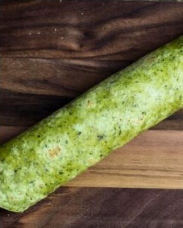 Spinach tortilla wrap with roast beef before being sliced.