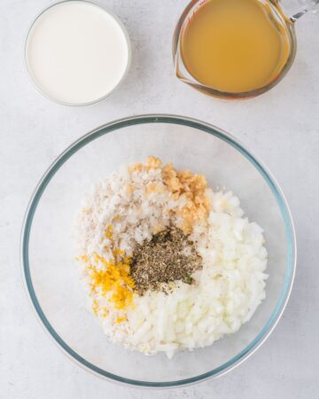 A glass bowl with rice and ingredients for slow cooker chicken broccoli rice.