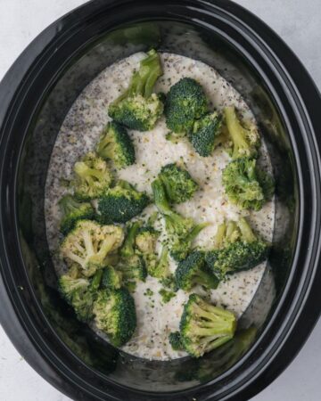 Broccoli added to a slow cooker vessel with rice for a chicken brocoli rice casserole.