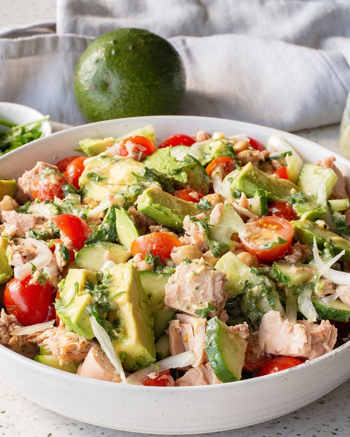 A white bowl with avocado chickpea tuna salad.